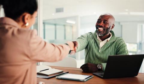 Two people shaking hands across a table image